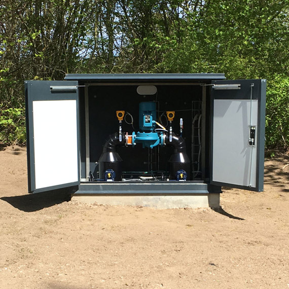 DESMI pump system installed in an outdoor cabinet surrounded by trees.
