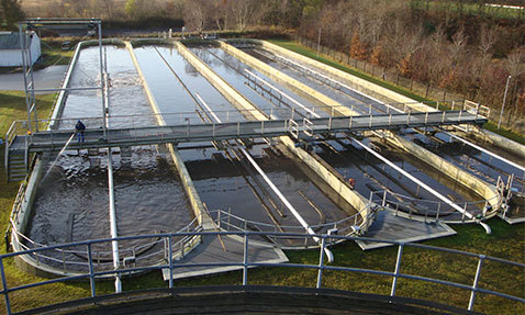 Wastewater treatment plant with multiple rectangular sedimentation tanks and walkways.