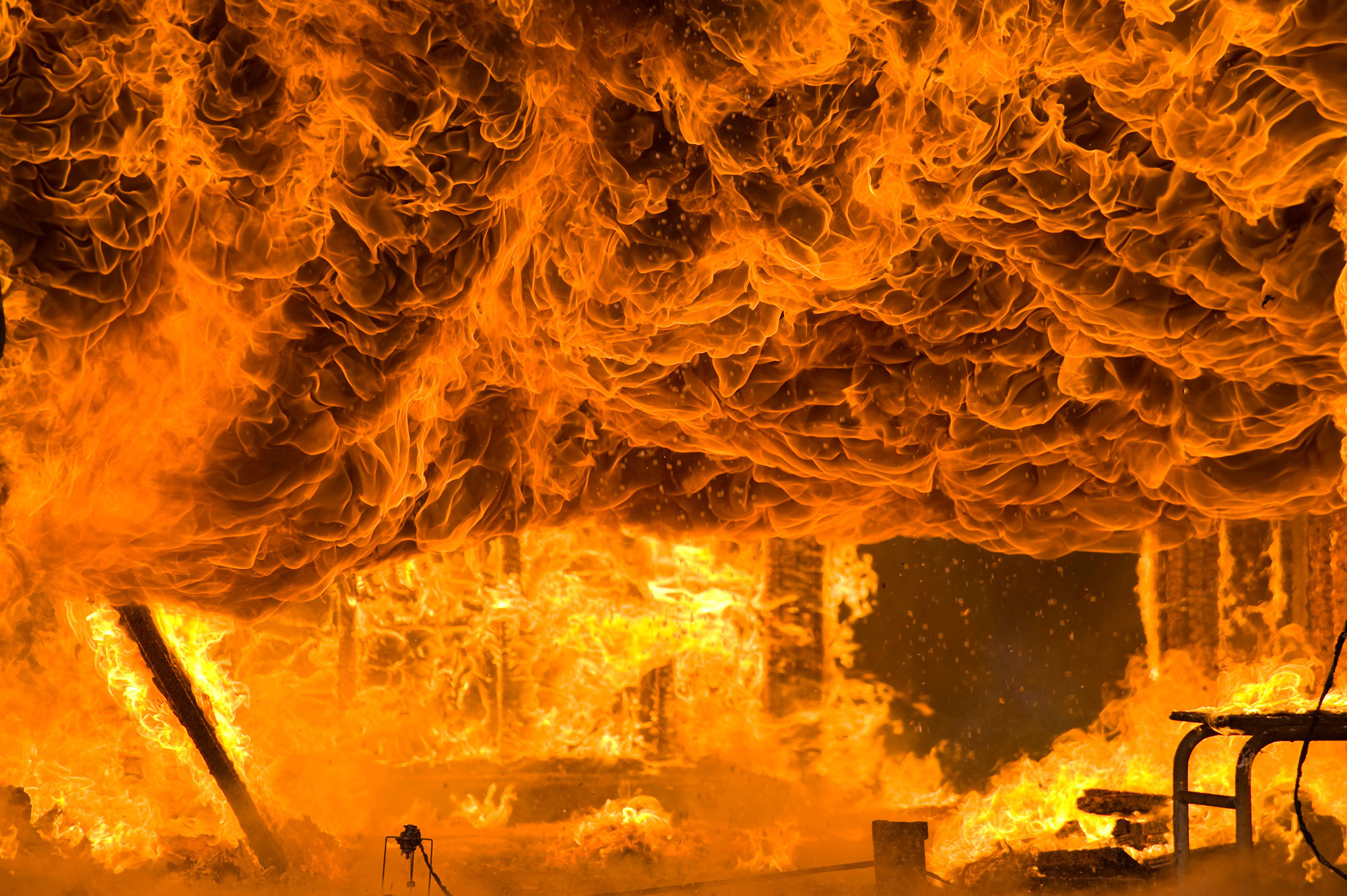 Intense fire engulfing a structure, with flames and smoke swirling dramatically.