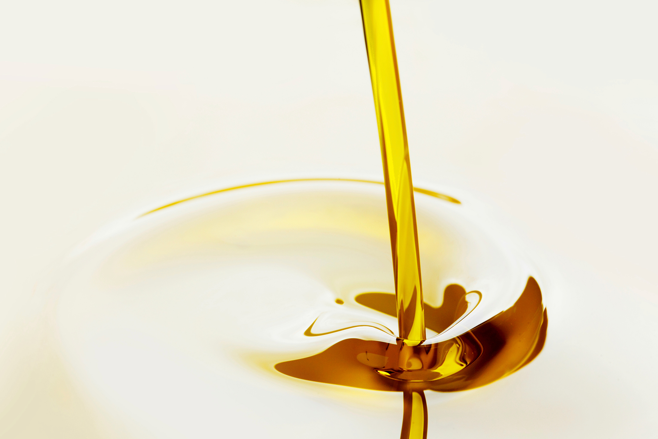 Golden liquid being poured, creating ripples on the surface.