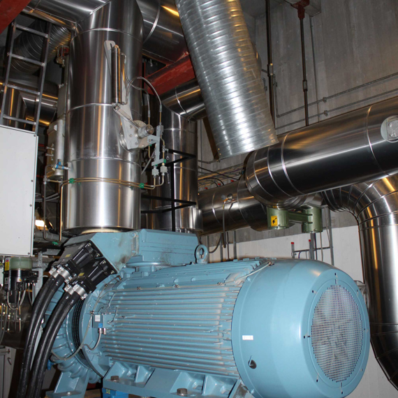 Large industrial pump with surrounding metal ducts for fluid handling.