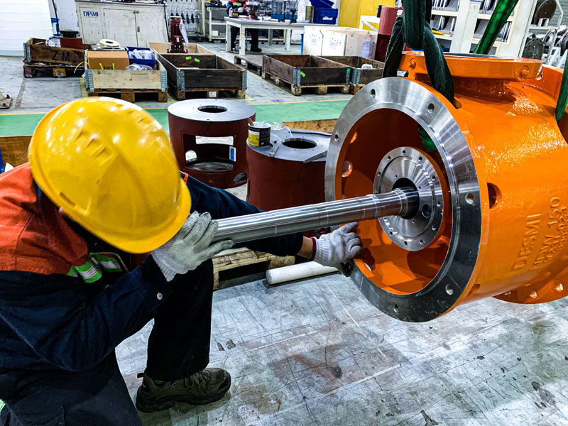 Worker installs shaft in DESMI pump housing for fluid handling.