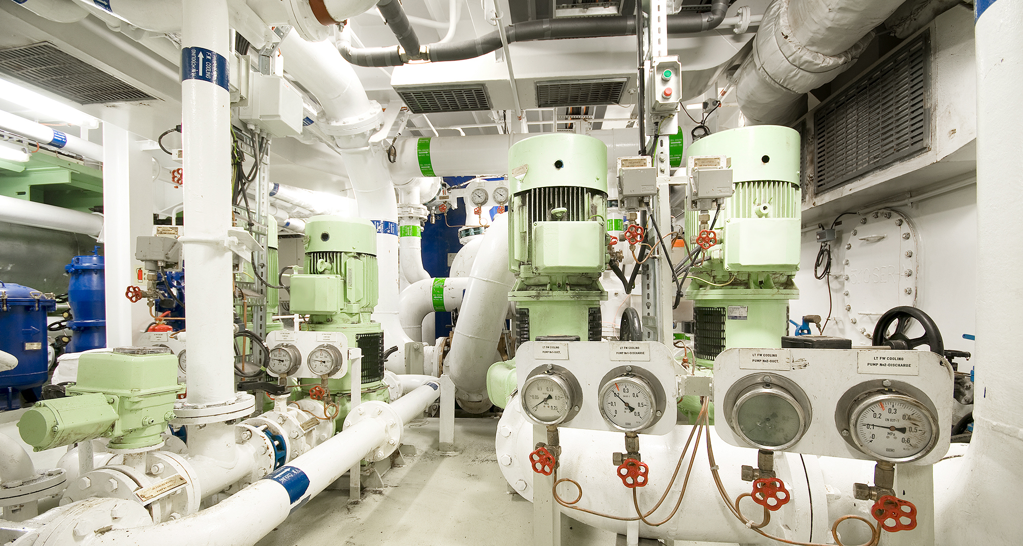 Industrial room with multiple pumps and gauges for fluid handling systems.