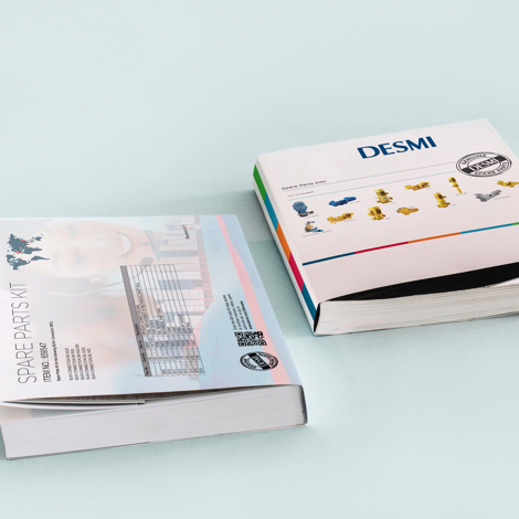 Two DESMI spare parts kits catalogs on a light blue surface.