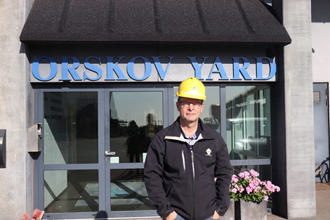 Man in a yellow hard hat stands in front of Orskov Yard entrance.