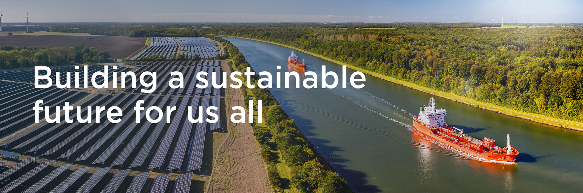 Solar panels, wind turbines, and ships on a canal promoting sustainability.