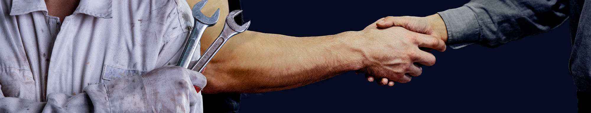 Mechanic holding wrenches and shaking hands with another person in agreement.