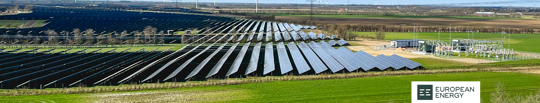 Solar power plant with numerous panels in a green landscape, European Energy logo visible.
