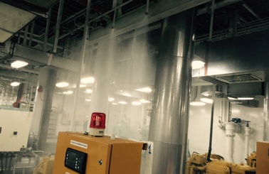 Industrial room with active fire suppression system and control panel with red light.