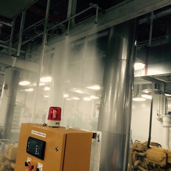 Industrial room with active fire suppression system and control panel with red light.