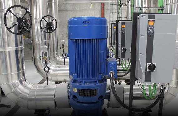 Blue DESMI pump with control panels and pipes in an industrial facility.