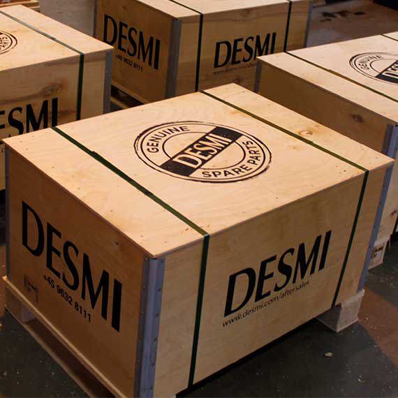 Wooden crates labeled "DESMI Genuine Spare Parts" stacked on pallets.